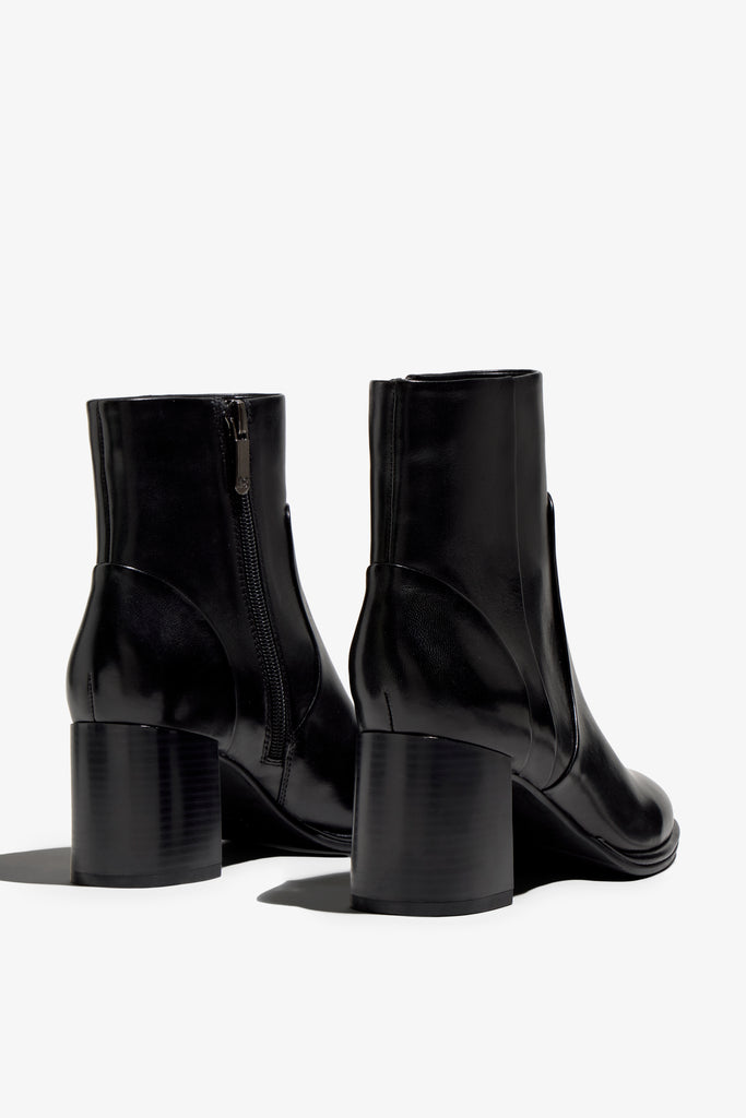 black leather ankle boot features a 65 mm heel, zipper, accentuated stitching, rubber sole, and plateau.