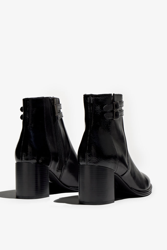 black leather ankle boot features a 65 mm heel, zipper, accentuated stitching, rubber sole, plateau and buckle straps.